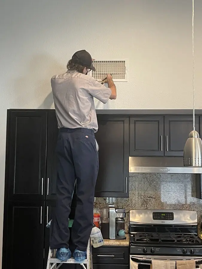 Technician inspecting an air vent during HVAC service in Perryville